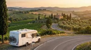 Camper parcheggiato su strada panoramica tra colline, vigneti e cipressi al tramonto in Italia